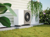 Wärmepumpe steht vor einer Hauswand im Garten