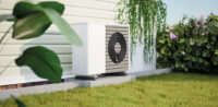 Wärmepumpe steht vor einer Hauswand im Garten