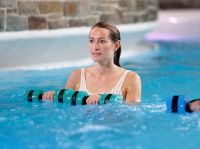 Eine Frau steht im Wasser und konzentriert sich auf einen Aqua-Fitness-Kurs.