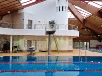 Rettungsschwimmer (m/w/d) auf Abruf Ein leeres Schwimmerbecken mit Bahnabtrennungen und einem Sprungturm.