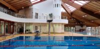 Rettungsschwimmer (m/w/d) auf Abruf Ein leeres Schwimmerbecken mit Bahnabtrennungen und einem Sprungturm.