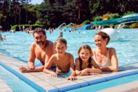 Familie am Beckenrand des Waldbad-Freizeitbeckens
