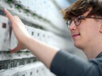 Elektroniker für Betriebstechnik (m/w/d) Ein junger Mann arbeitet an Zählern.