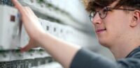 Elektroniker für Betriebstechnik (m/w/d) Ein junger Mann arbeitet an Zählern.
