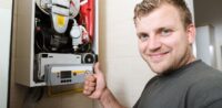 Ein Monteur vor einer Gastherme zeigt Daumen hoch.