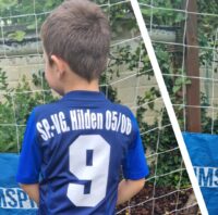 Ein Junge zeigt sein blau-weißes Fußball-Trikot des SV Hilden von hinten.