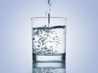 Wasser wird in ein Trinkglas eingegossen.