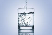 Wasser wird in ein Trinkglas eingegossen.